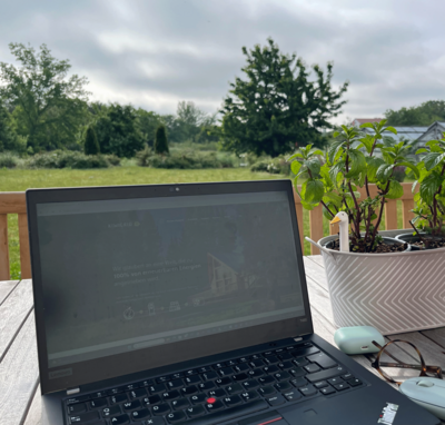 Laptop mit Kiwigrid-Homepage steht auf Tisch im grünem Umfeld.