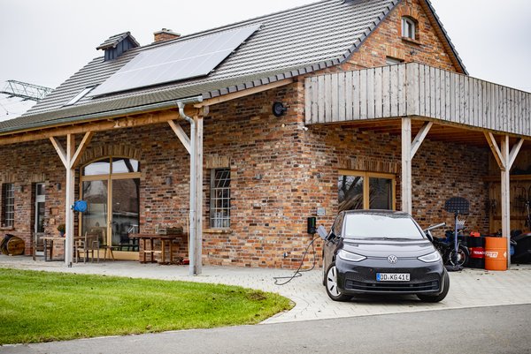 Moderne Scheune mit Solaranlage und E-Auto.