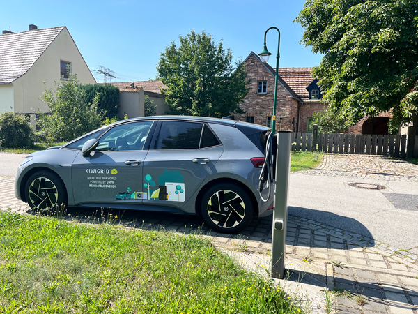 Gray e-car with Kiwigrid branding at charging station.