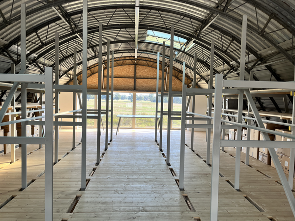 Eingerüstetes lichtdurchflutetes oberes Stockwerk des Hangars mit geschwungenem Dach.