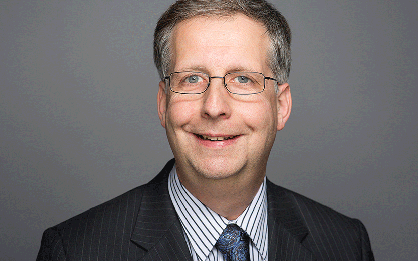 The picture shows Dr. Frank Schlichting - a smiling man with glasses in a suit.